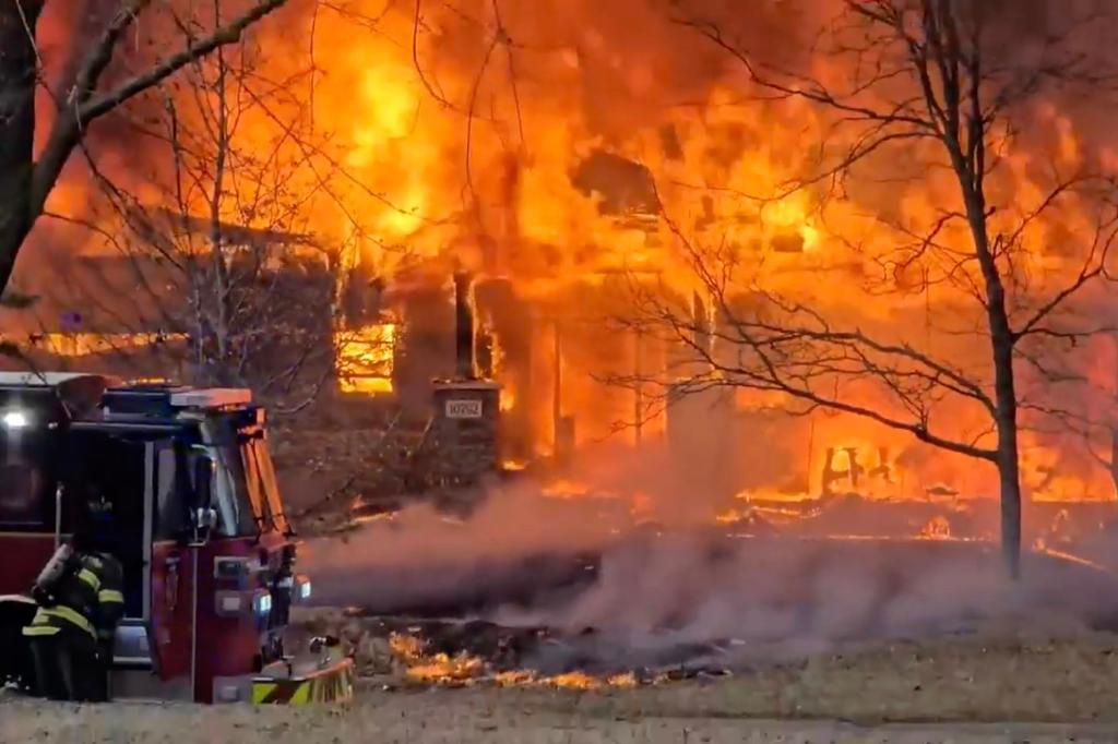 Fire crews and local residents at the scene of an airplane crash into a house, causing a large fire, in Brooklyn Park, Minnesota.